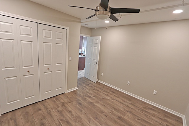 unfurnished bedroom with hardwood / wood-style floors, ceiling fan, and a closet