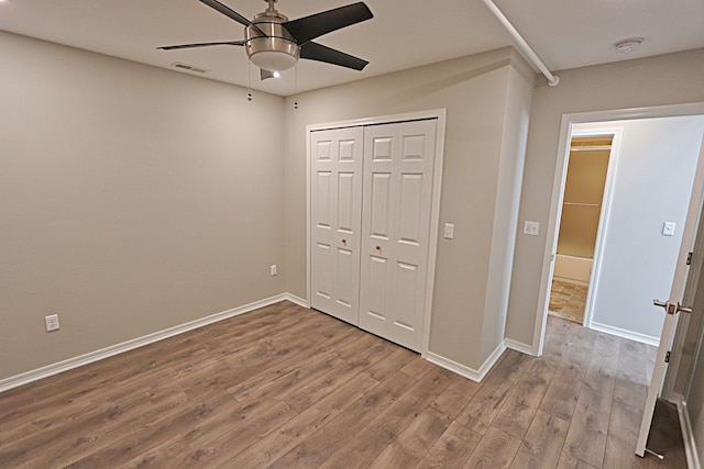 unfurnished bedroom featuring ceiling fan, a closet, and hardwood / wood-style floors