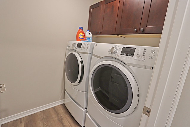 laundry room featuring washer and clothes dryer, cabinets, and light wood-type flooring