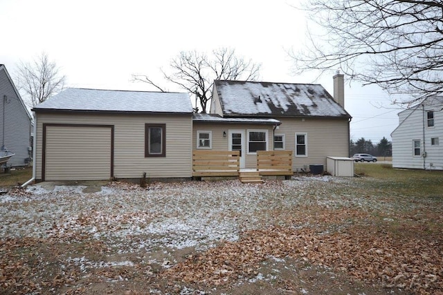 rear view of property featuring a garage and a wooden deck