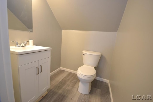 bathroom with lofted ceiling, vanity, toilet, and hardwood / wood-style floors