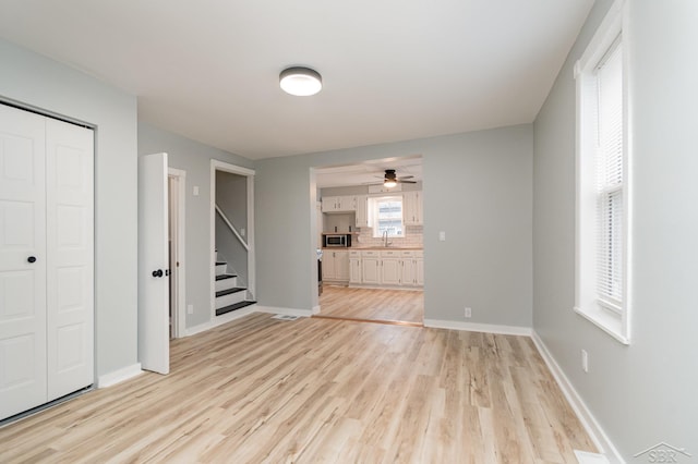 unfurnished living room featuring ceiling fan and light wood-type flooring