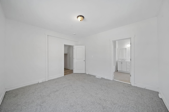 unfurnished bedroom featuring connected bathroom and light carpet