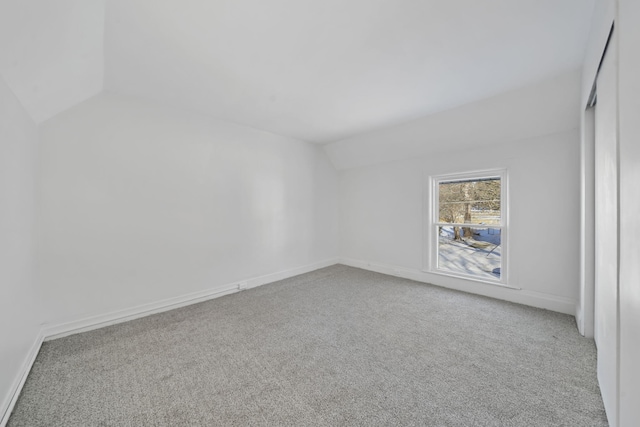 carpeted spare room featuring lofted ceiling