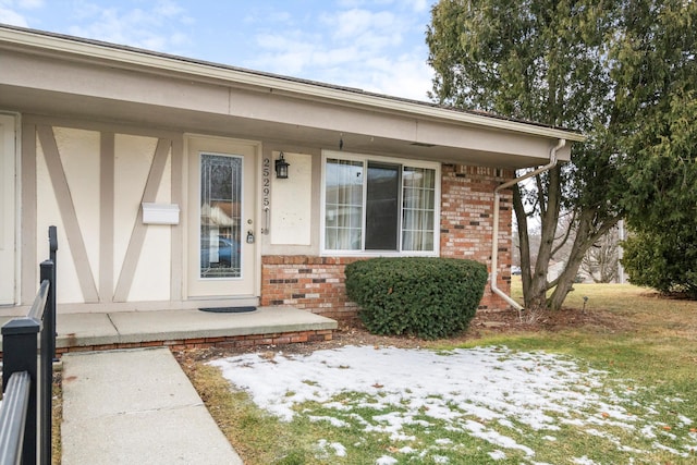 snow covered property entrance featuring a yard