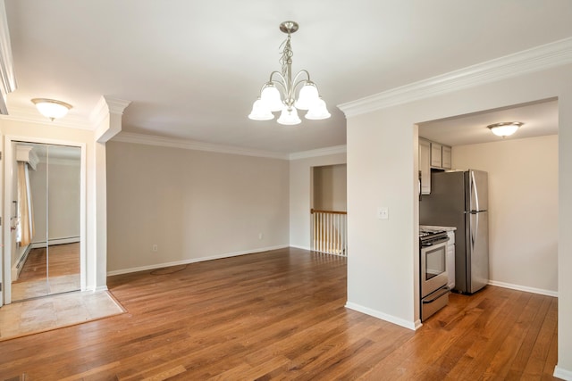 kitchen featuring an inviting chandelier, ornamental molding, appliances with stainless steel finishes, hardwood / wood-style flooring, and white cabinets