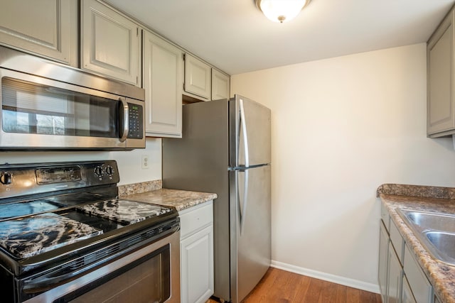 kitchen featuring stainless steel appliances, sink, and light hardwood / wood-style floors