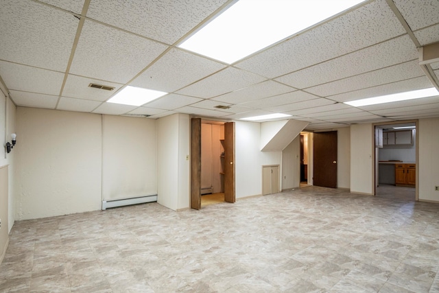 basement with a baseboard heating unit and a paneled ceiling