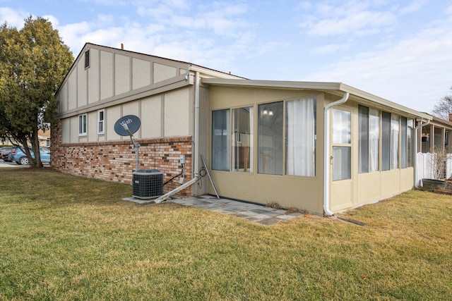 view of side of property featuring cooling unit, a yard, and a sunroom