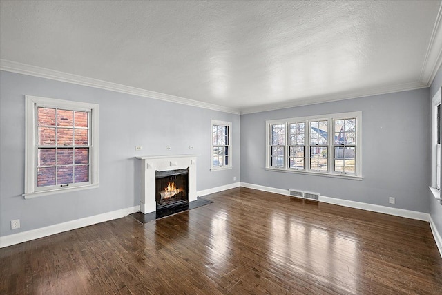 unfurnished living room with plenty of natural light, crown molding, dark wood-type flooring, and a high end fireplace