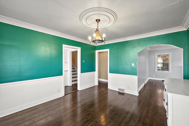 spare room with a notable chandelier, dark hardwood / wood-style floors, and crown molding