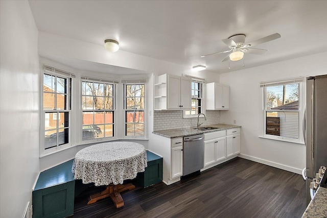 kitchen featuring appliances with stainless steel finishes, tasteful backsplash, light stone counters, dark wood-type flooring, and white cabinetry