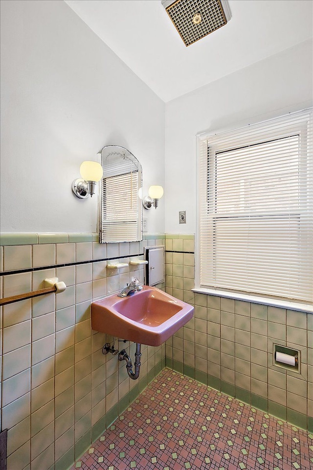 bathroom with tile walls, a healthy amount of sunlight, and sink