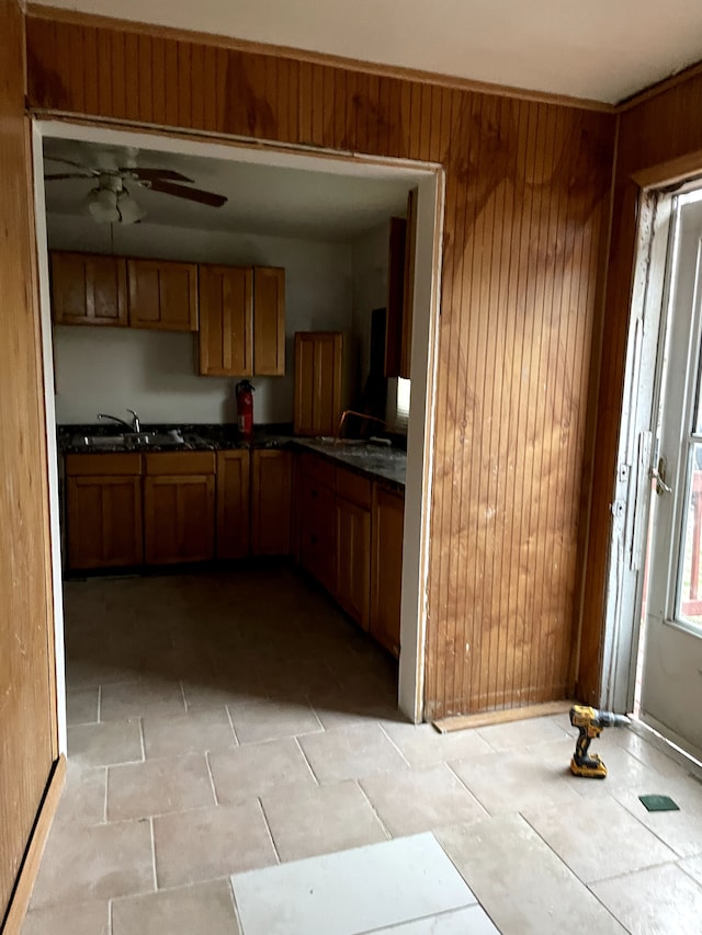 kitchen featuring wooden walls, sink, and ceiling fan