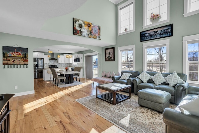 living room with a towering ceiling and light wood-type flooring