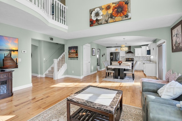 living room featuring sink, a towering ceiling, and light hardwood / wood-style floors