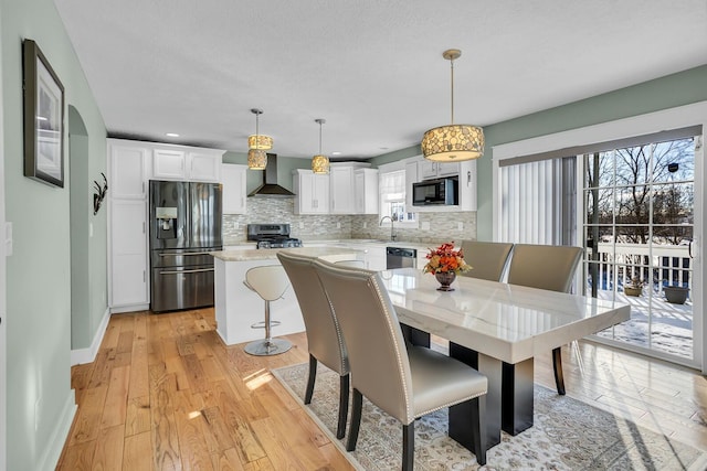 dining space featuring a wealth of natural light, sink, and light wood-type flooring