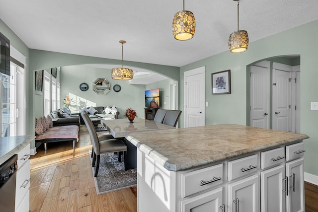 kitchen featuring white cabinets, decorative light fixtures, a kitchen island, and dishwasher