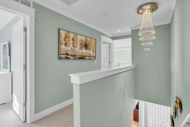 hallway with light colored carpet, ornamental molding, and an inviting chandelier