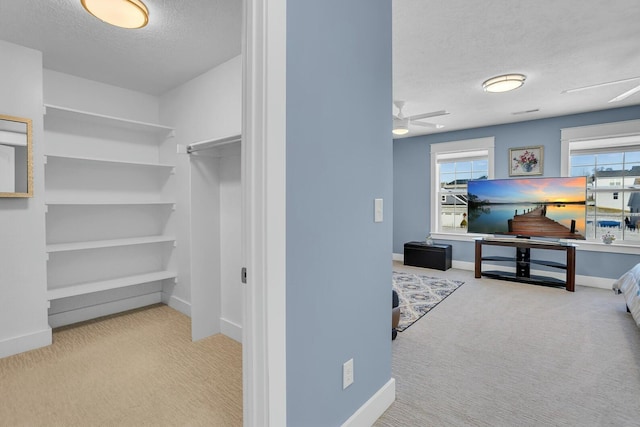 spacious closet featuring ceiling fan and light carpet