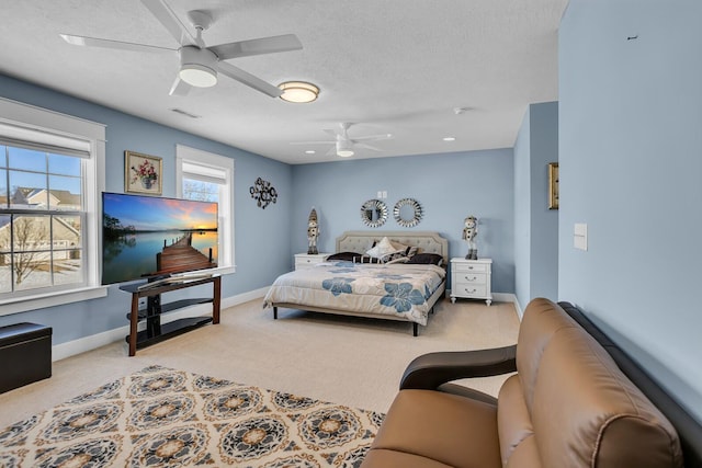 bedroom with a textured ceiling, light colored carpet, and ceiling fan