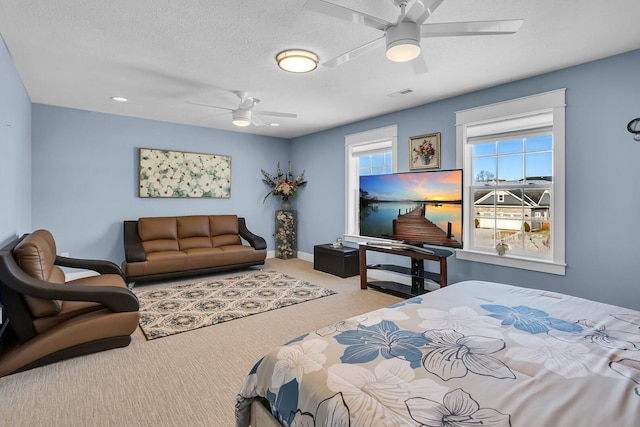 bedroom featuring ceiling fan, light colored carpet, and a textured ceiling