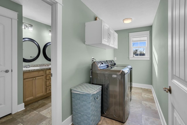 clothes washing area featuring cabinets, sink, and washing machine and clothes dryer