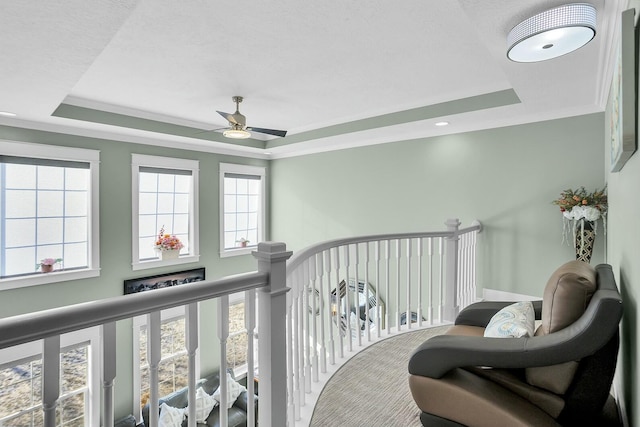 interior space featuring ornamental molding, a raised ceiling, ceiling fan, and plenty of natural light