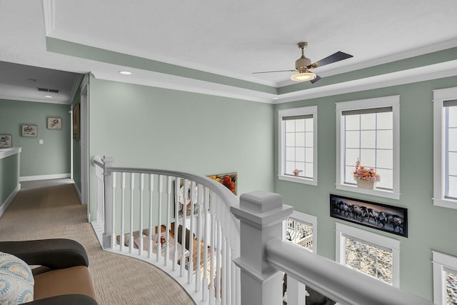 corridor featuring carpet flooring, ornamental molding, and a tray ceiling