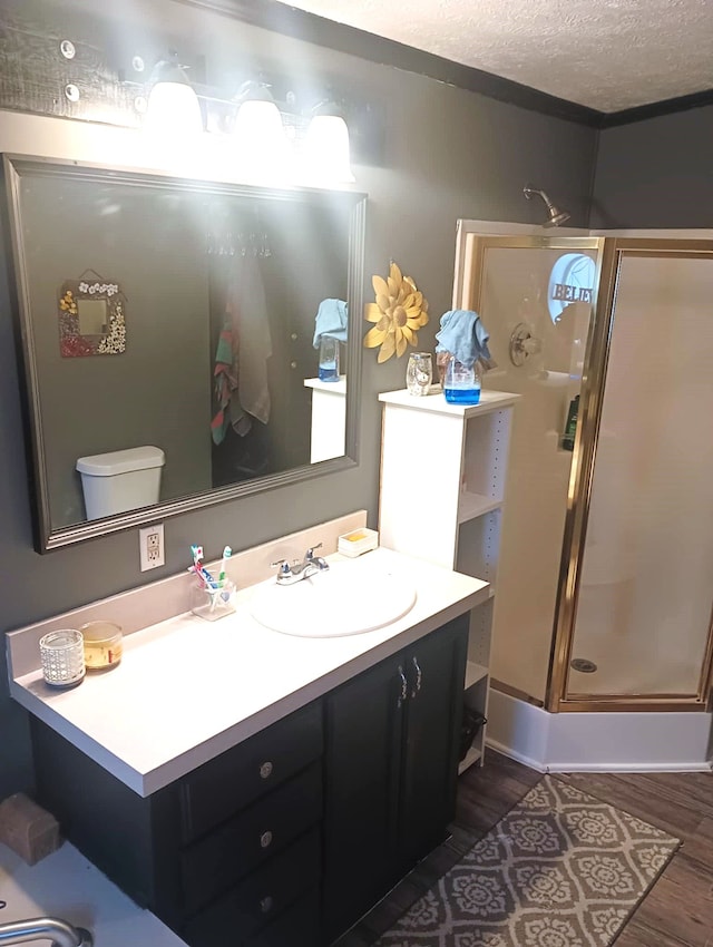 bathroom featuring walk in shower, a textured ceiling, vanity, hardwood / wood-style floors, and toilet