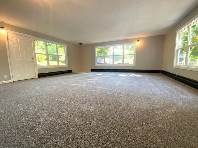 carpeted spare room with a baseboard heating unit