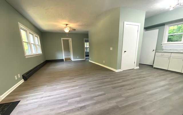 unfurnished living room featuring a textured ceiling, a baseboard radiator, light hardwood / wood-style flooring, and ceiling fan