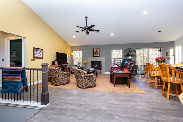 living room with a wealth of natural light, light wood-type flooring, ceiling fan, and a tiled fireplace