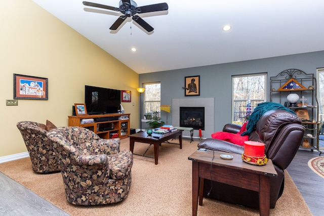 living room with hardwood / wood-style floors, vaulted ceiling, ceiling fan, and a tiled fireplace