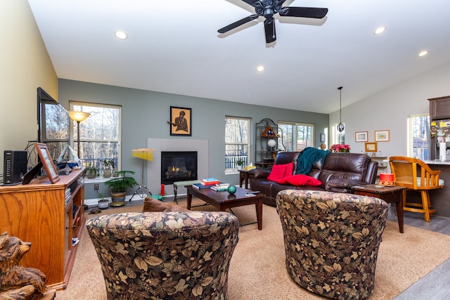 living room featuring vaulted ceiling, ceiling fan, a healthy amount of sunlight, and a tiled fireplace