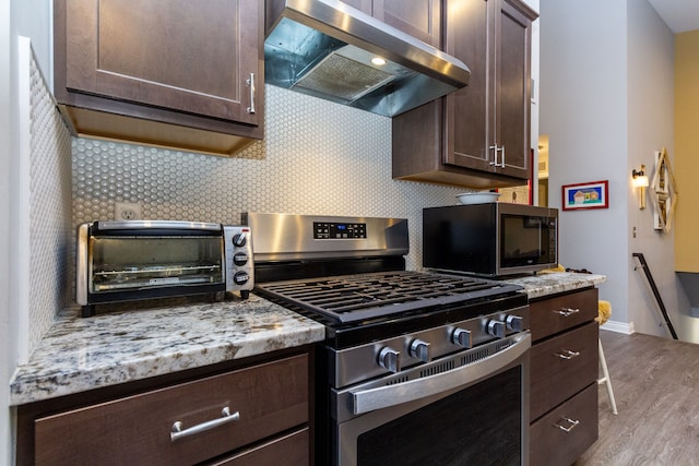 kitchen featuring decorative backsplash, appliances with stainless steel finishes, dark brown cabinetry, light hardwood / wood-style flooring, and range hood