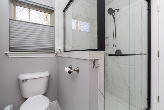 bathroom featuring toilet and a shower with door