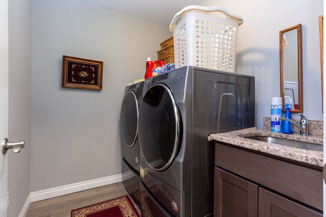 laundry area featuring washer and dryer, wood-type flooring, and sink