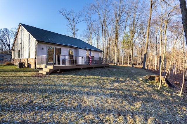 rear view of property featuring cooling unit, a lawn, and a wooden deck