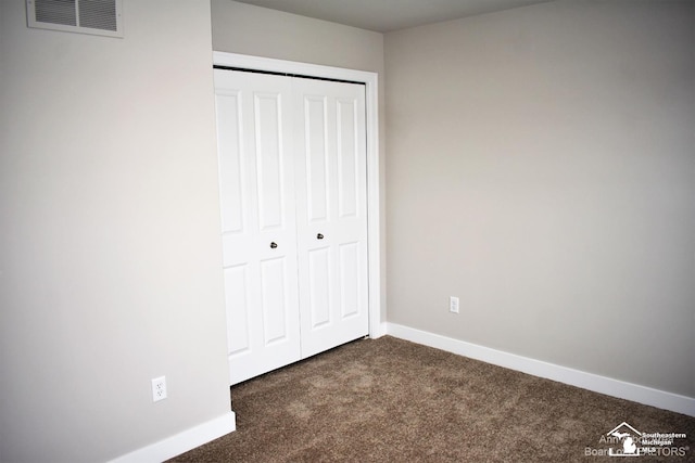 unfurnished bedroom featuring a closet and dark colored carpet