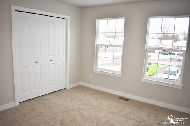 unfurnished bedroom with a closet, light carpet, and multiple windows