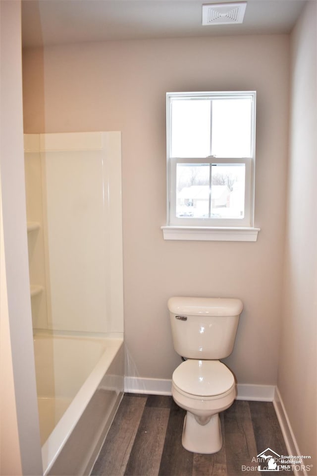 bathroom featuring wood-type flooring, toilet, and a bathing tub