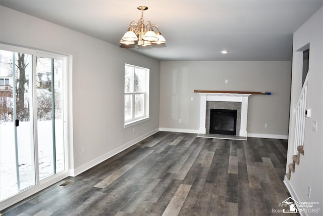 unfurnished living room with an inviting chandelier, a fireplace, and dark hardwood / wood-style floors