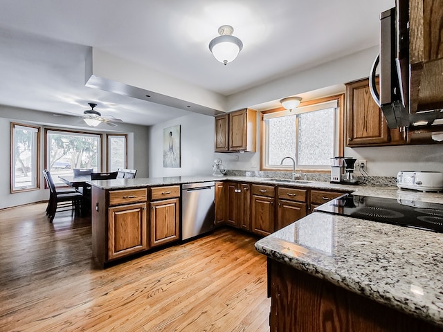 kitchen with kitchen peninsula, light stone countertops, appliances with stainless steel finishes, ceiling fan, and sink