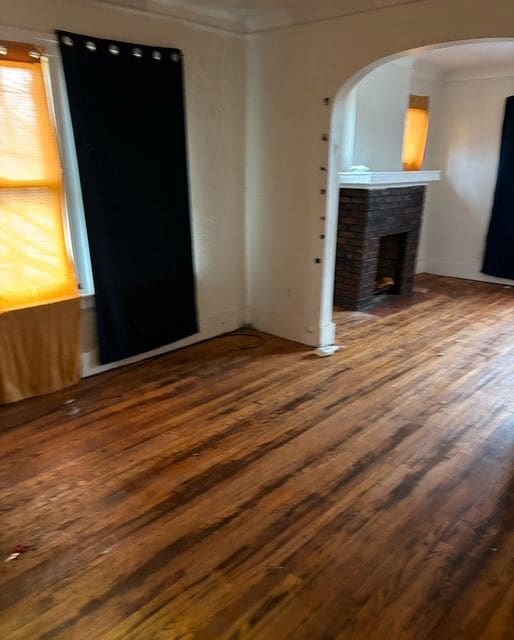 unfurnished living room with hardwood / wood-style floors and a brick fireplace