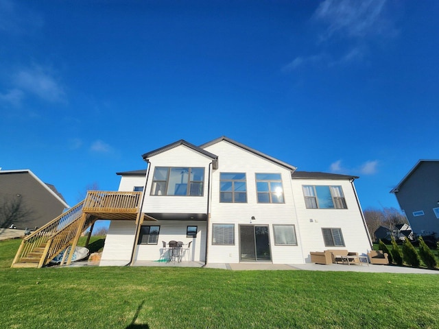 rear view of house featuring a lawn, a wooden deck, and a patio