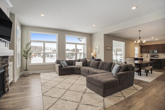 living room with a fireplace, light hardwood / wood-style floors, and a notable chandelier