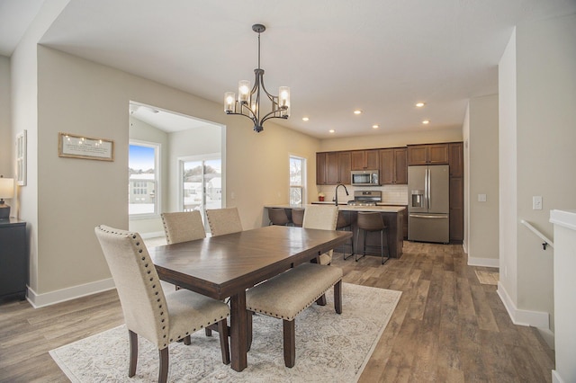 dining area with dark hardwood / wood-style floors, lofted ceiling, sink, and a chandelier