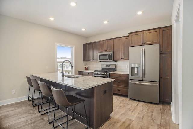 kitchen featuring sink, light wood-type flooring, appliances with stainless steel finishes, tasteful backsplash, and kitchen peninsula