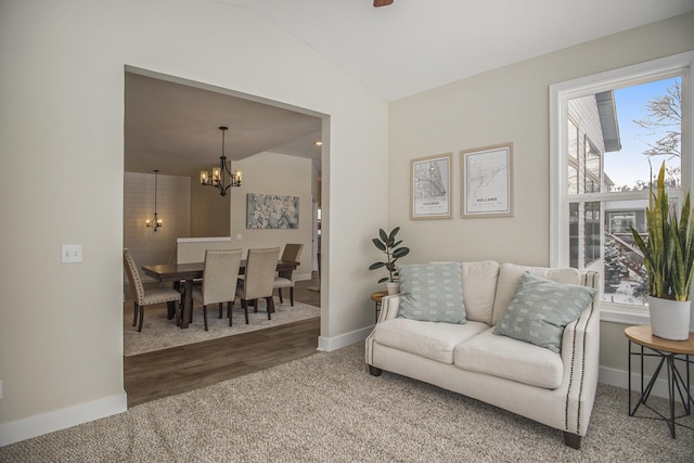 carpeted living room featuring vaulted ceiling and a notable chandelier